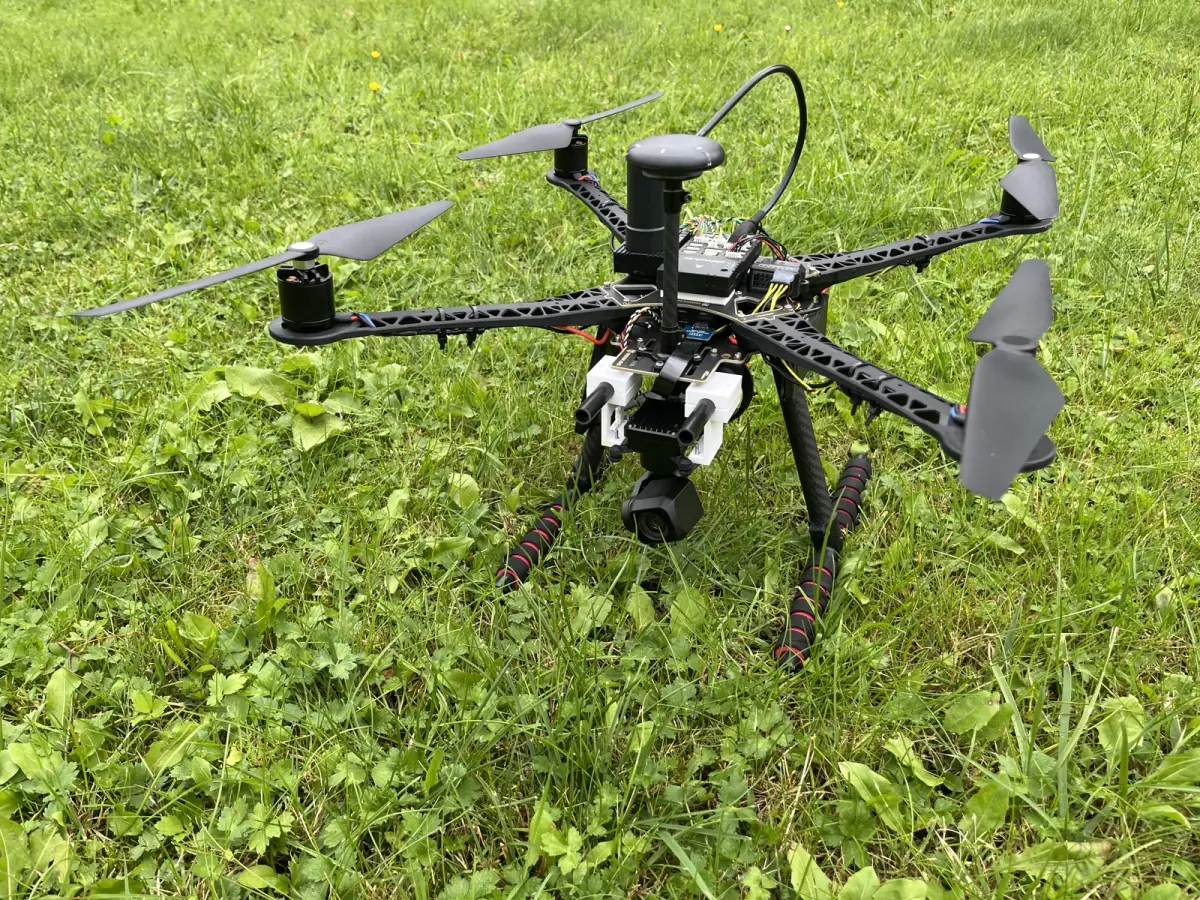 UAV1, a four-rotor drone with a camera underneath, standing on grass